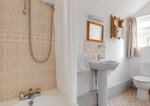 a bathroom with a sink and a toilet and a shower at Carters Cottage in Slaughterford