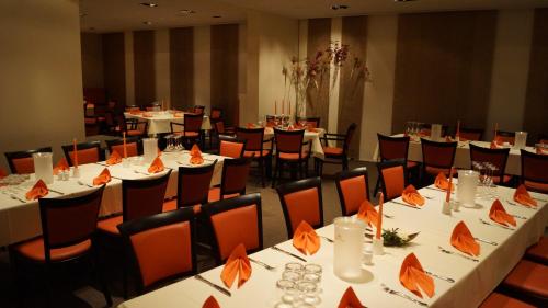 ein Esszimmer mit weißen Tischen und orangefarbenen Stühlen in der Unterkunft Hotel Goldener Löwe in Waldheim