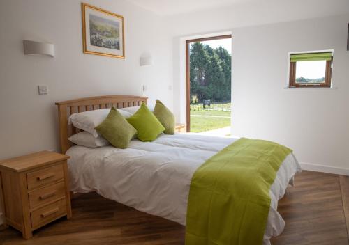 a bedroom with a bed with green pillows and a window at Brighton Hopper Hut in Goudhurst