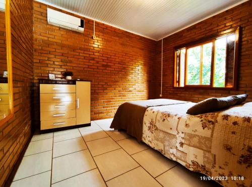 um quarto com uma cama, uma cómoda e uma janela em Casa de campo com acesso ao Rio em Encantado