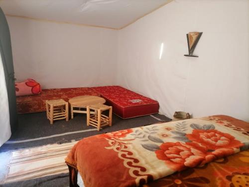 a room with two beds and a table and chairs at Erg Chegaga Desert Night in El Gouera