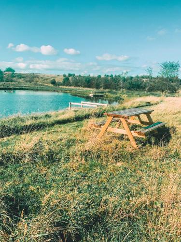 a picnic table in the grass next to a river at Rossendale Holiday Cottages & Spa in Rossendale