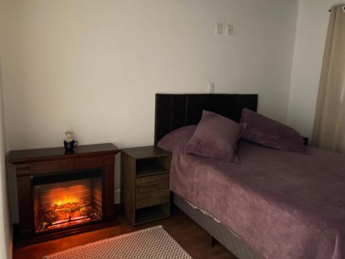 a bedroom with a fireplace next to a bed at Apartamentos Dumont in Monte Verde