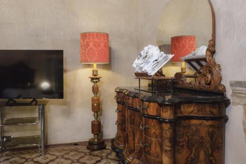 a room with a mirror and a dresser with a television at Foresteria Palazzo Guazzoni Zaccaria in Cremona