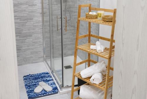 ein Badezimmer mit einer Dusche und einem Holzregal mit Handtüchern in der Unterkunft Marchese 124 in Bari