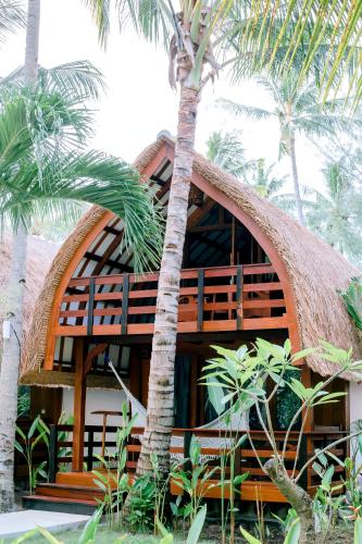a resort with palm trees in front of a building at Island View Bar & Bungalow in Gili Air