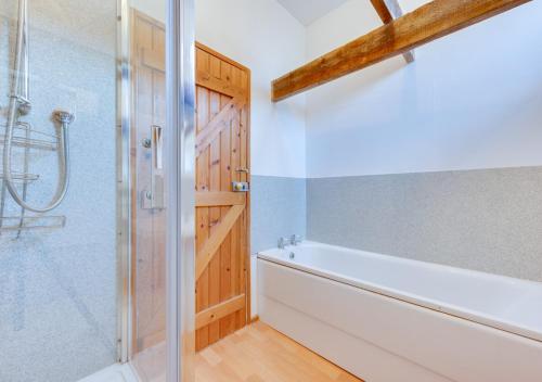 a bathroom with a shower and a white tub at Firs Coach House in Rolvenden