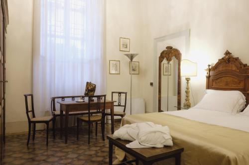 a bedroom with a bed and a table and chairs at Foresteria Palazzo Guazzoni Zaccaria in Cremona