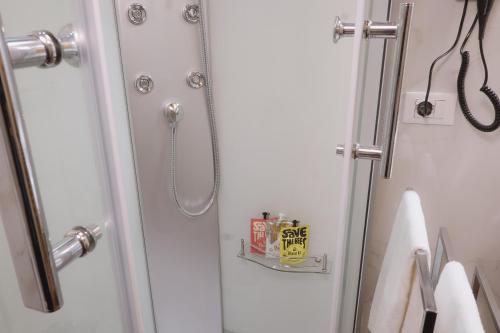 a shower in a bathroom with white walls and white towels at Foresteria Palazzo Guazzoni Zaccaria in Cremona