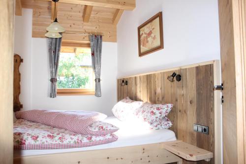 a bedroom with a bed with a wooden headboard and a window at Ferienhaus Schwab in Mittersill