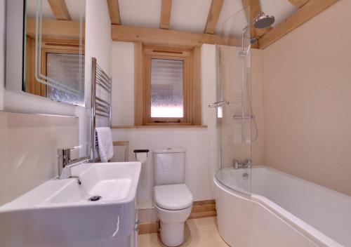 a bathroom with a toilet and a tub and a sink at Glebe Cottage in Stone