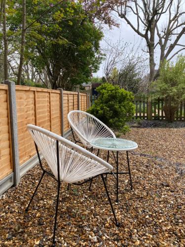 two white chairs and a table in a yard at Ealing Garden Flat in Ealing