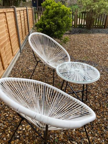 two white benches sitting next to a fence at Ealing Garden Flat in Ealing