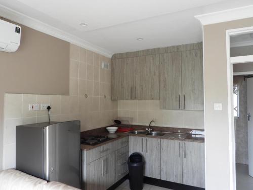 a kitchen with wooden cabinets and a refrigerator at 2 bedroomed apartment with en-suite and kitchenette - 2065 in Harare