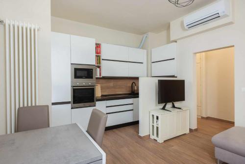 uma cozinha com armários brancos e uma mesa com televisão em Ci Vuole Leggerezza Apartment Free Parking em Bolonha