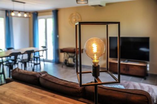 - une lampe dans le salon avec un canapé dans l'établissement MAISON TOUT CONFORT - NATURE - CALME - 98m2, à Le Verdier