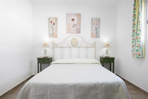 a white bedroom with a white bed and two tables at Casa Josisa - Solo Familias in Conil de la Frontera