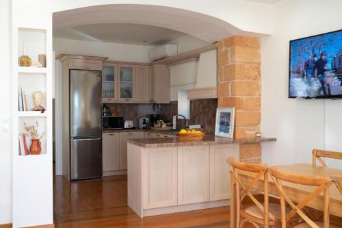 a kitchen with a stainless steel refrigerator and a table at Naias Aegina, Sea-front apartment 95 sqm in Egina