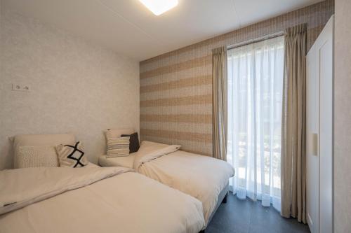 two beds in a room with a window at Meerzicht 24 - Luxury family accommodation with beautiful lake side view in Uitgeest