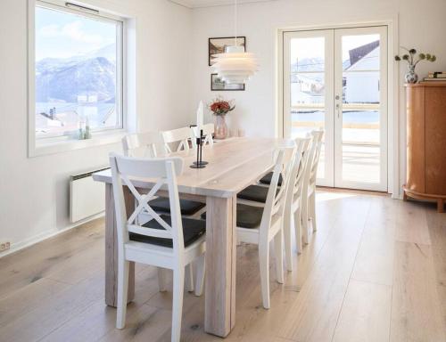 a white dining room table with white chairs and a large window at Fjord Panorama in Stranda