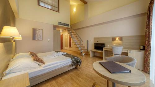 1 dormitorio con cama, mesa y escalera en Wellness Hotel Patince, en Patince