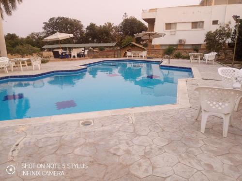 a swimming pool with a table and chairs next to a building at فيلا الزيات in Sarābiyūm