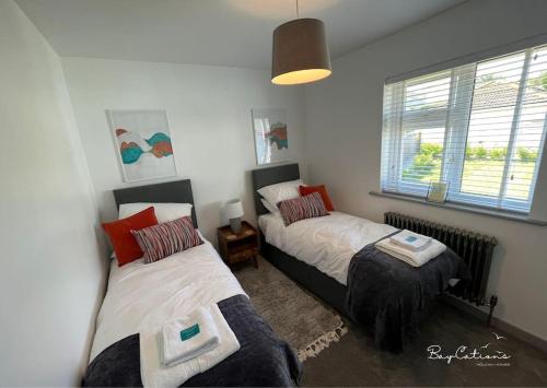 a bedroom with two beds and a window at Stylish Brixham home, sleeps 7, parking & garden in Brixham