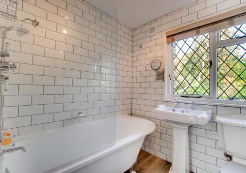 een witte badkamer met een bad en een wastafel bij Marigold Cottage in Rolvenden