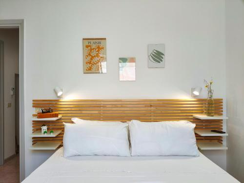 una camera con letto bianco e testiera in legno di Da Mimma di Casa Camilla Journey a Marina di Pescoluse