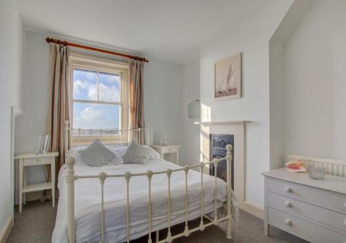 a white bedroom with a bed and a window at Lower Coastguard Cottage in Hastings