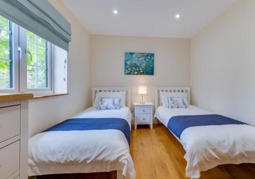 two beds in a room with two windows at Maple Cottage in Woodchurch