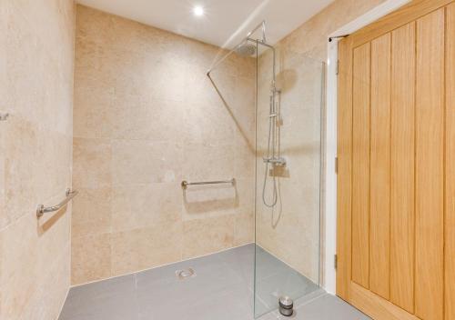 a bathroom with a shower with a glass door at Maple Cottage in Woodchurch