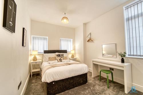 a bedroom with a bed and a desk with a mirror at Guest Homes - The Bell Apartment in Stourbridge