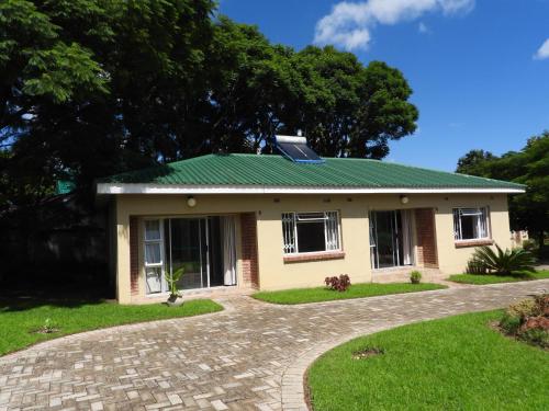 a small yellow house with a green roof at 2 bedroomed apartment with en-suite and kitchenette - 2068 in Harare