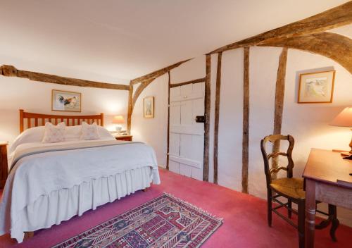 a bedroom with a bed and a desk and a table at Old Cobblers Cottage at Kings Head House in Sissinghurst