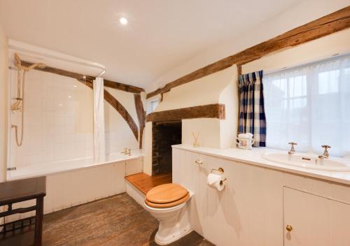 a bathroom with a toilet and a tub and a sink at Old Cobblers Cottage at Kings Head House in Sissinghurst