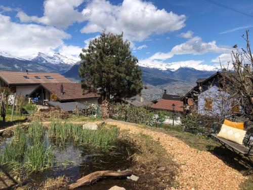 a house with a pond and mountains in the background at La Majorie de Nendaz in Nendaz