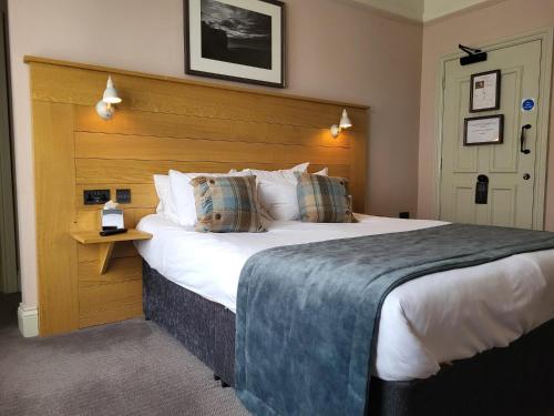 a bedroom with a large bed with a wooden headboard at The Black Hat in Ilkley