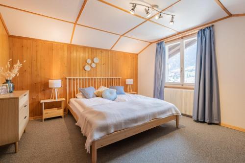 a bedroom with a large bed and a window at The Eiger Express Apartment - GRINDELHOMES in Grindelwald