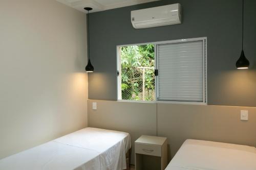 a room with two beds and a window at Pousada Terra Rossa in São José do Rio Pardo