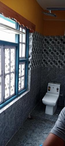 a bathroom with a toilet and a window at Drishtee Homestay in Rongli