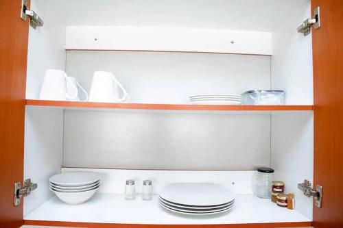 une cuisine avec des assiettes et des bols blancs sur une étagère dans l'établissement Chic Modern House on Neasden - 2085, à Bulawayo