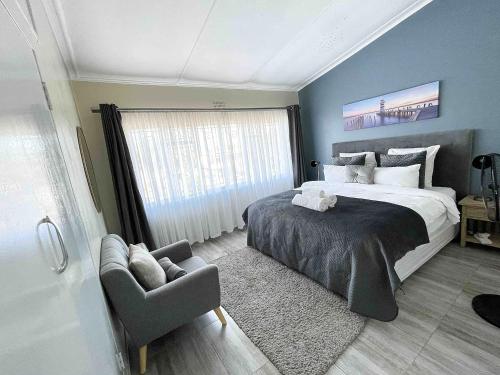 a bedroom with a bed and a chair and a window at Chic Modern House on Neasden - 2085 in Bulawayo