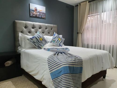 a bedroom with a large bed with a blanket and a window at Posh 3 bedroomed guesthouse in Hillside with pool - 2039 in Bulawayo