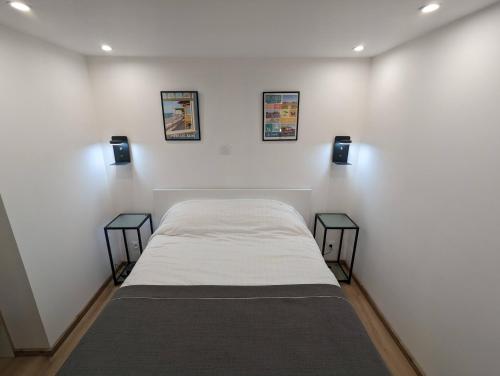 een witte kamer met een bed en twee bijzettafels bij A deux pas mer et falaises in Mers-les-Bains