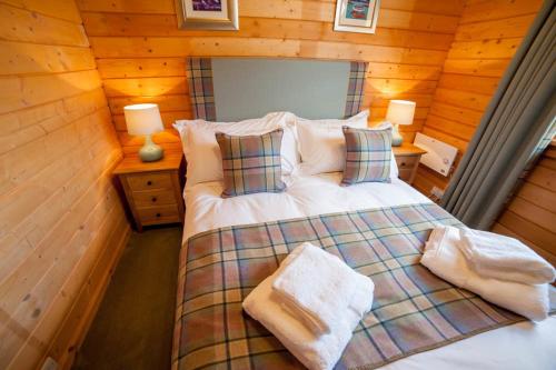 a bedroom with a bed in a log cabin at Stable Lodge in Drymen