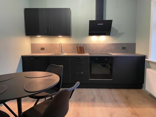 a kitchen with black cabinets and a table and chairs at Randalín in Åkirkeby