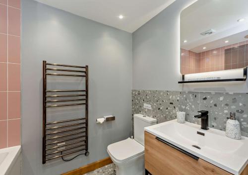 een badkamer met een wastafel, een toilet en een spiegel bij River Birch in Beckley