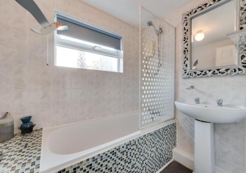 a bathroom with a tub and a sink and a mirror at Millers Cottage in Broadstairs