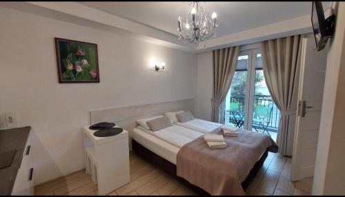 Habitación blanca con cama y lámpara de araña. en Apartamenty Biała Perła, en Ustroń